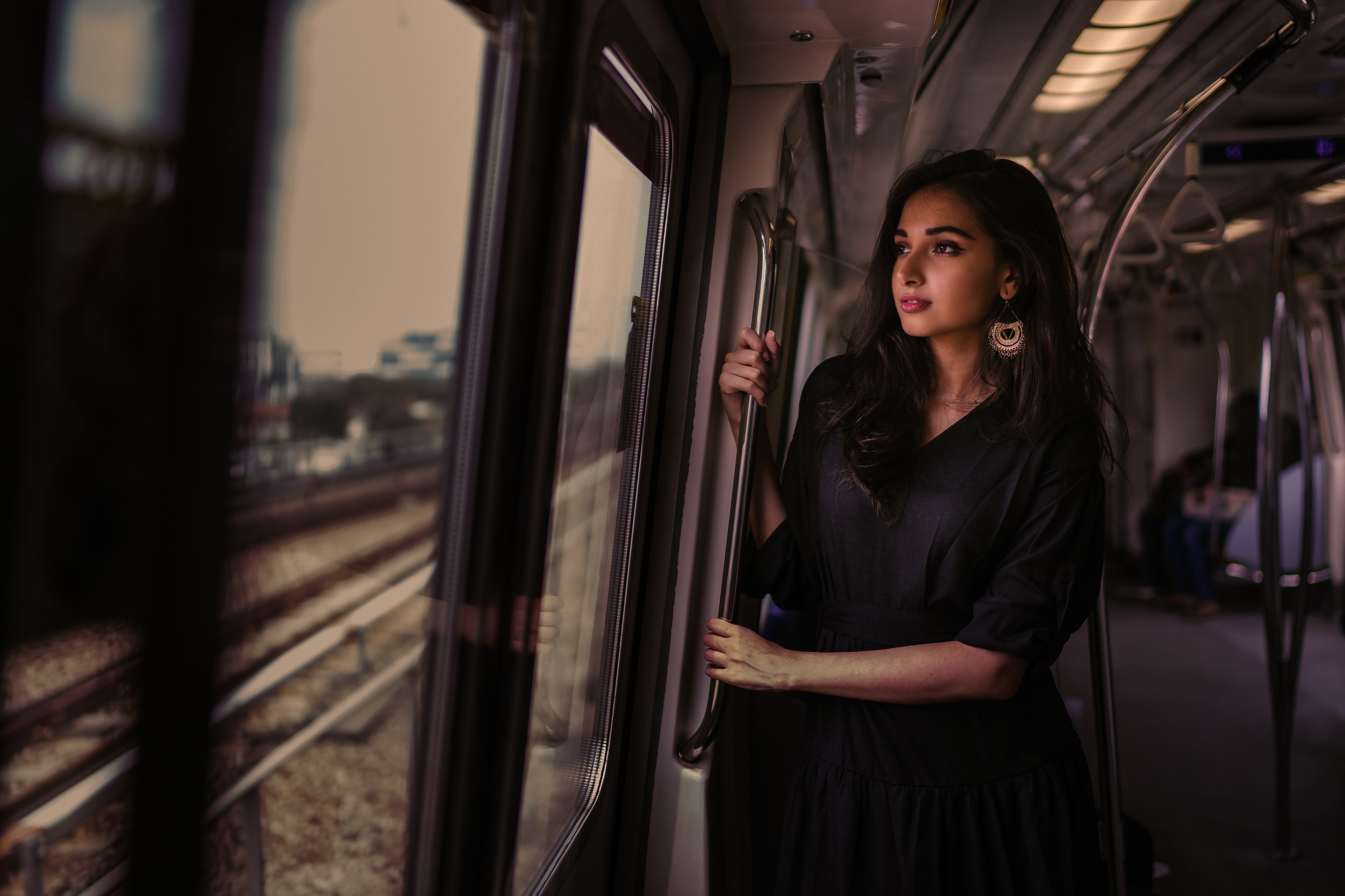women standing in train holding metal rail while looking outside 1575665254 - Women Standing In Train Holding Metal Rail While Looking Outside -